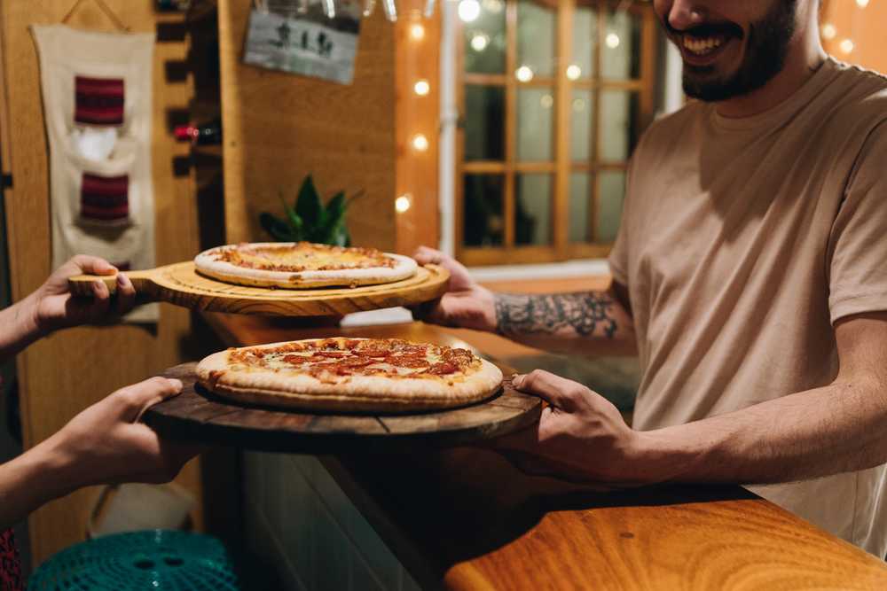 En man serverar pizzor i en pizzeria